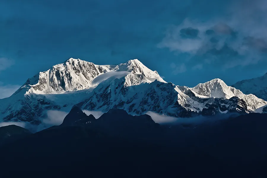 Auf die Bergspitzen einer schneebedeckten Bergkette fällt Sonnenlicht.